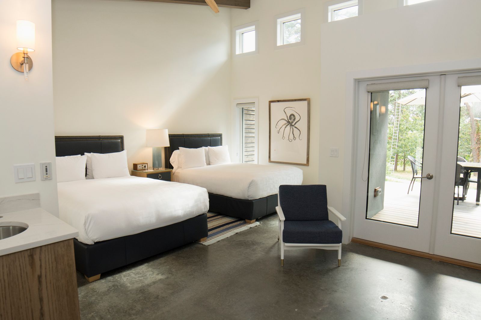 A bright guest room with two queen beds made with white linens